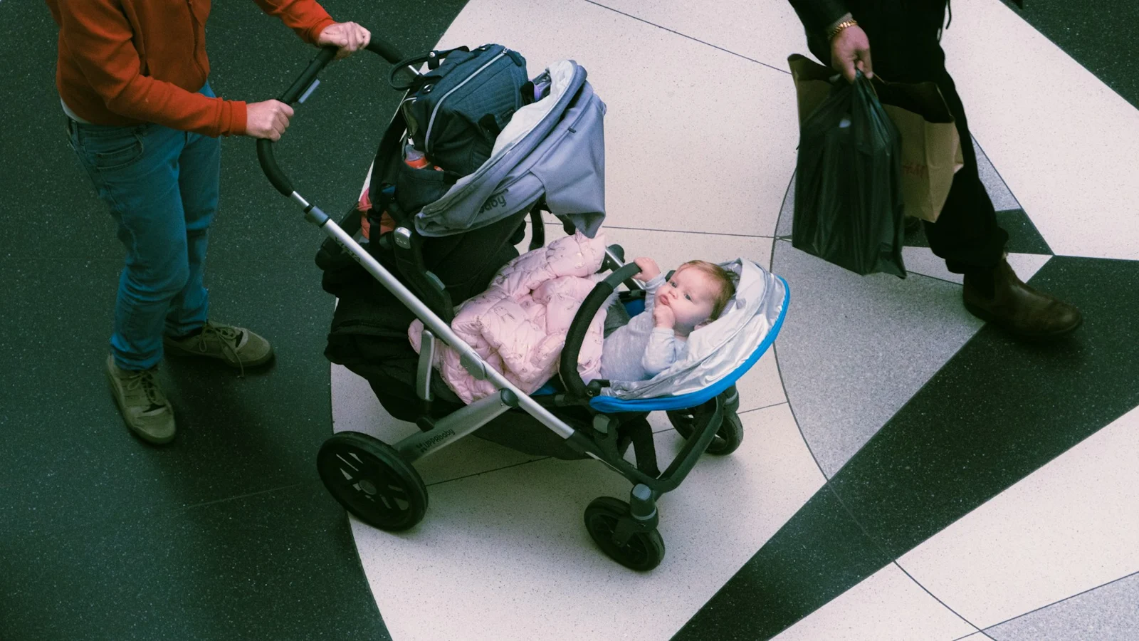 Parent pushing a baby in a stroller indoors；第三方摄影参考
